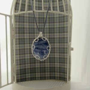 Large oval pendant featuring denim blue sodalite with a silver plated wire wrap. Hanging from grey cord 24 inches. One of a kind, designed and created in the Isle of Skye