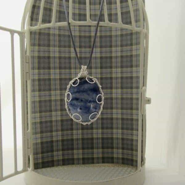 Large oval pendant featuring denim blue sodalite with a silver plated wire wrap. Hanging from grey cord 24 inches. One of a kind, designed and created in the Isle of Skye