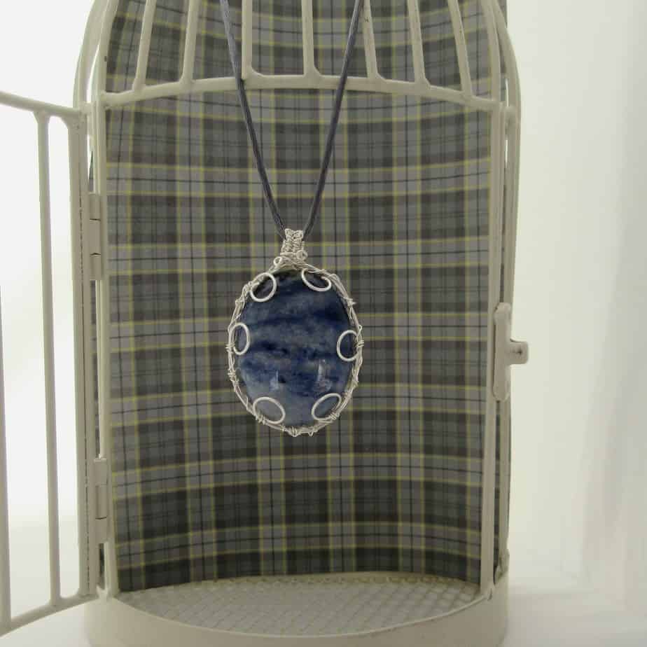 Large oval pendant featuring denim blue sodalite with a silver plated wire wrap. Hanging from grey cord 24 inches. One of a kind, designed and created in the Isle of Skye