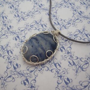 Large oval pendant featuring denim blue sodalite with a silver plated wire wrap. Hanging from grey cord 24 inches. One of a kind, designed and created in the Isle of Skye