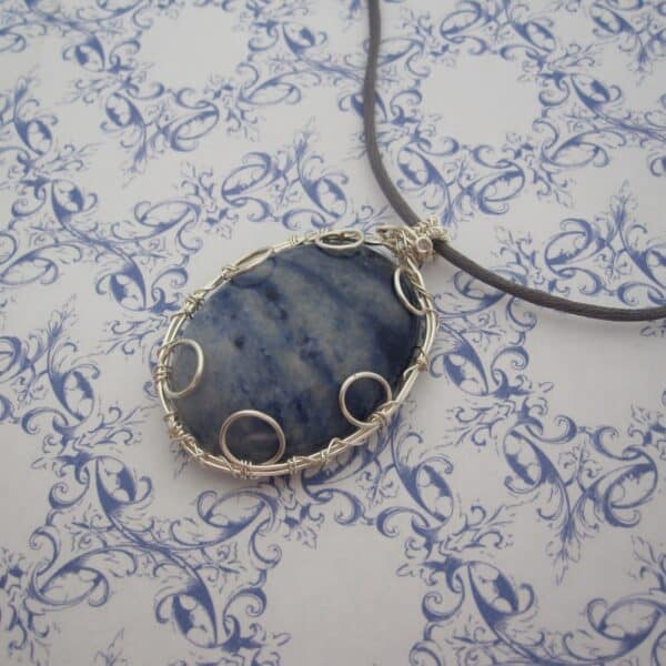 Large oval pendant featuring denim blue sodalite with a silver plated wire wrap. Hanging from grey cord 24 inches. One of a kind, designed and created in the Isle of Skye