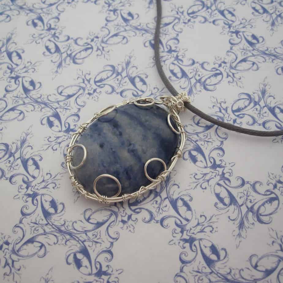 Large oval pendant featuring denim blue sodalite with a silver plated wire wrap. Hanging from grey cord 24 inches. One of a kind, designed and created in the Isle of Skye