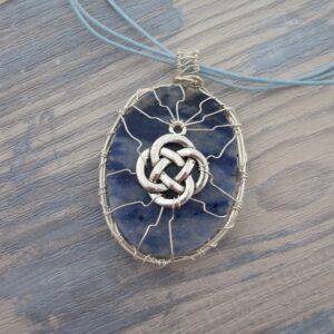 Back of oval sodalite pendant showing wire work with celtic knotwork. Silver plated wire. Hanging from grey cord 24 inches. One of a kind, designed and created in the Isle of Skye