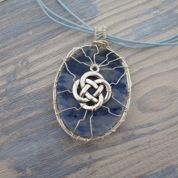 Back of oval sodalite pendant showing wire work with celtic knotwork. Silver plated wire. Hanging from grey cord 24 inches. One of a kind, designed and created in the Isle of Skye