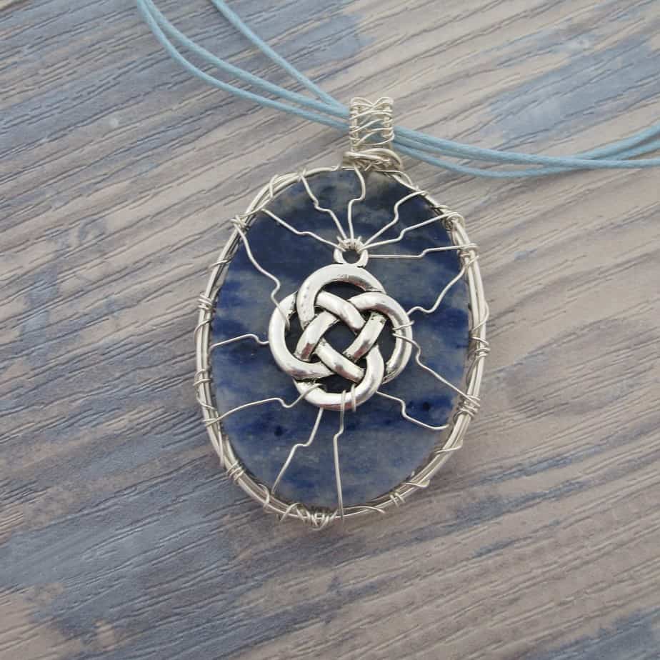 Back of oval sodalite pendant showing wire work with celtic knotwork. Silver plated wire. Hanging from grey cord 24 inches. One of a kind, designed and created in the Isle of Skye