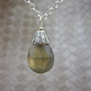 Designed and created in the Isle of Skye, this pendant necklace features a labradorite gemstone drop with silver plated bead cap. On 18 inch silver plated chain.