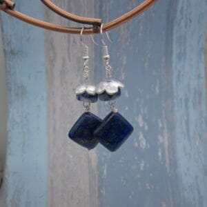 Drop Earrings with diamond shaped lapis lazuli and contrasting drum cut blue jasper. On silver plated ear wires with silver plated flower shaped bead cap.