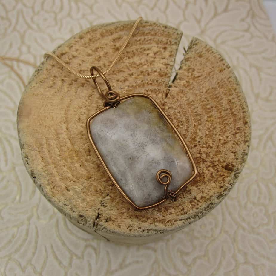 Rectangular pendant on gold plated snake chain. Fossil jasper with antique bronze wire frame finished with spiral detail at bottom.