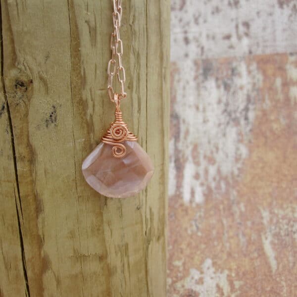 Pendant with tear drop shaped facet cut peach moonstone. With rose gold plated wire spiral and rose gold plated chain.