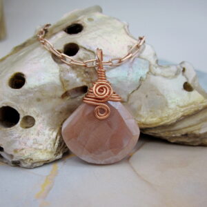 Pendant with tear drop shaped facet cut peach moonstone. With rose gold plated wire spiral and rose gold plated chain.