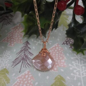 Pendant with tear drop shaped facet cut peach moonstone. With rose gold plated wire spiral and rose gold plated chain.