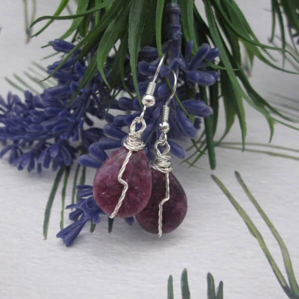 Drop earrings with tear drop shaped purple gemstone and twisted silver wire detail in flash across front.