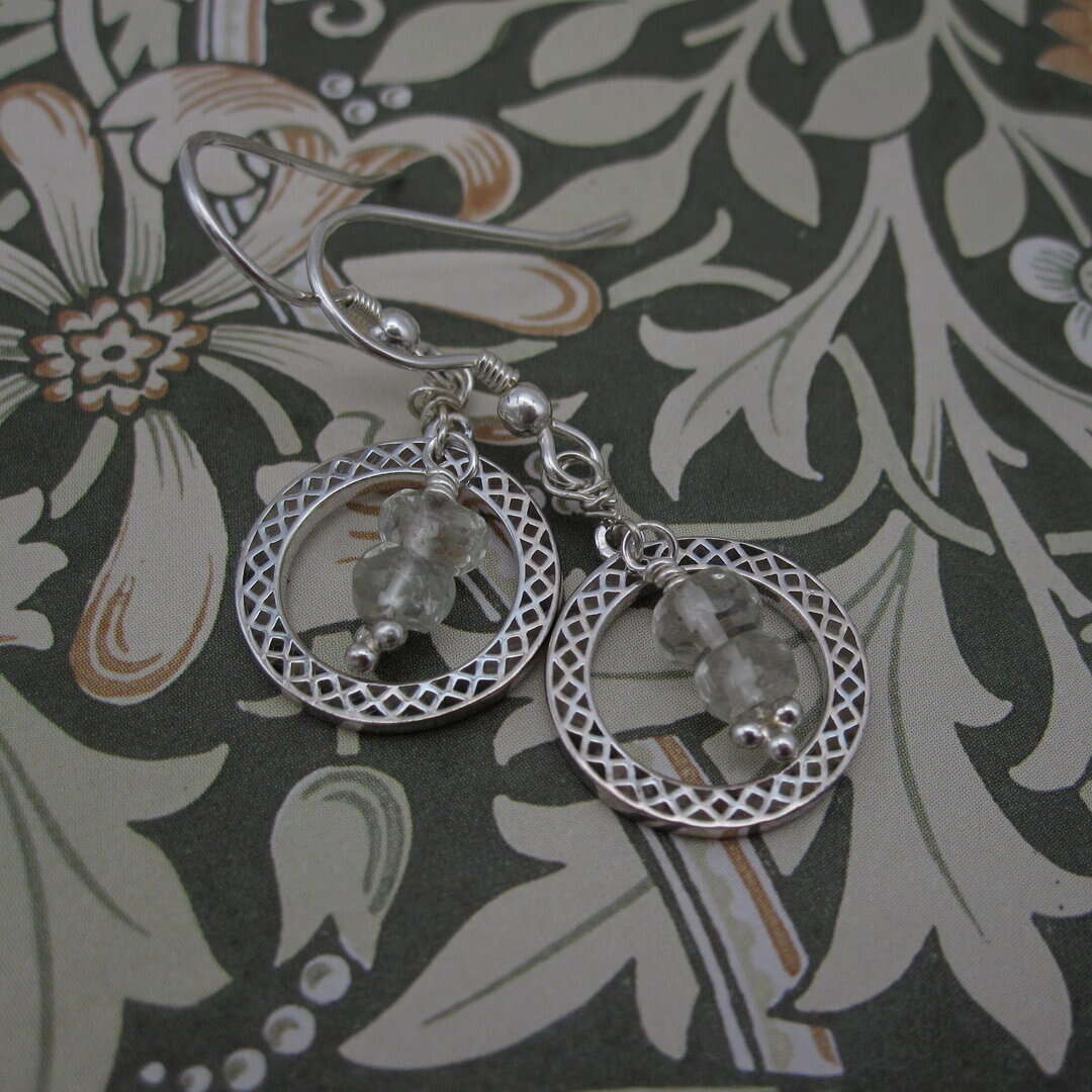 Earrings featuring a silver celtic knotwork circle with green amethyst drops inside. On sterling silver ear wires.
