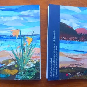 A photo of two notebooks of a single design, one face up, one face down. The design features daffodils by the sea.
