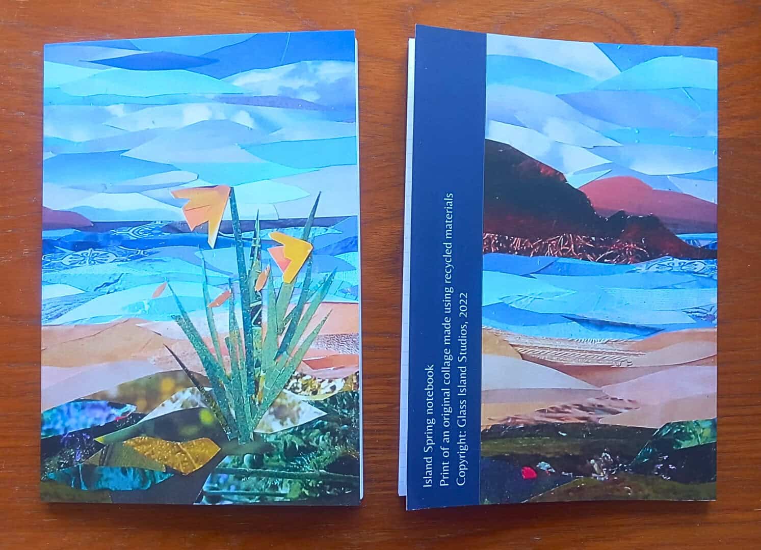 A photo of two notebooks of a single design, one face up, one face down. The design features daffodils by the sea.