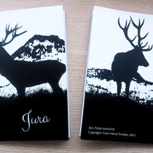 Photo of two notebooks of the same design featuring a black and white artist impression of two stags silhouetted against mountains. One notebook is face up and the other is face down.