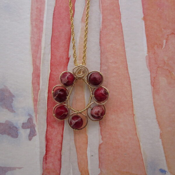 Red jasper pendant wire wrapped in garland shape with gold plated chain.